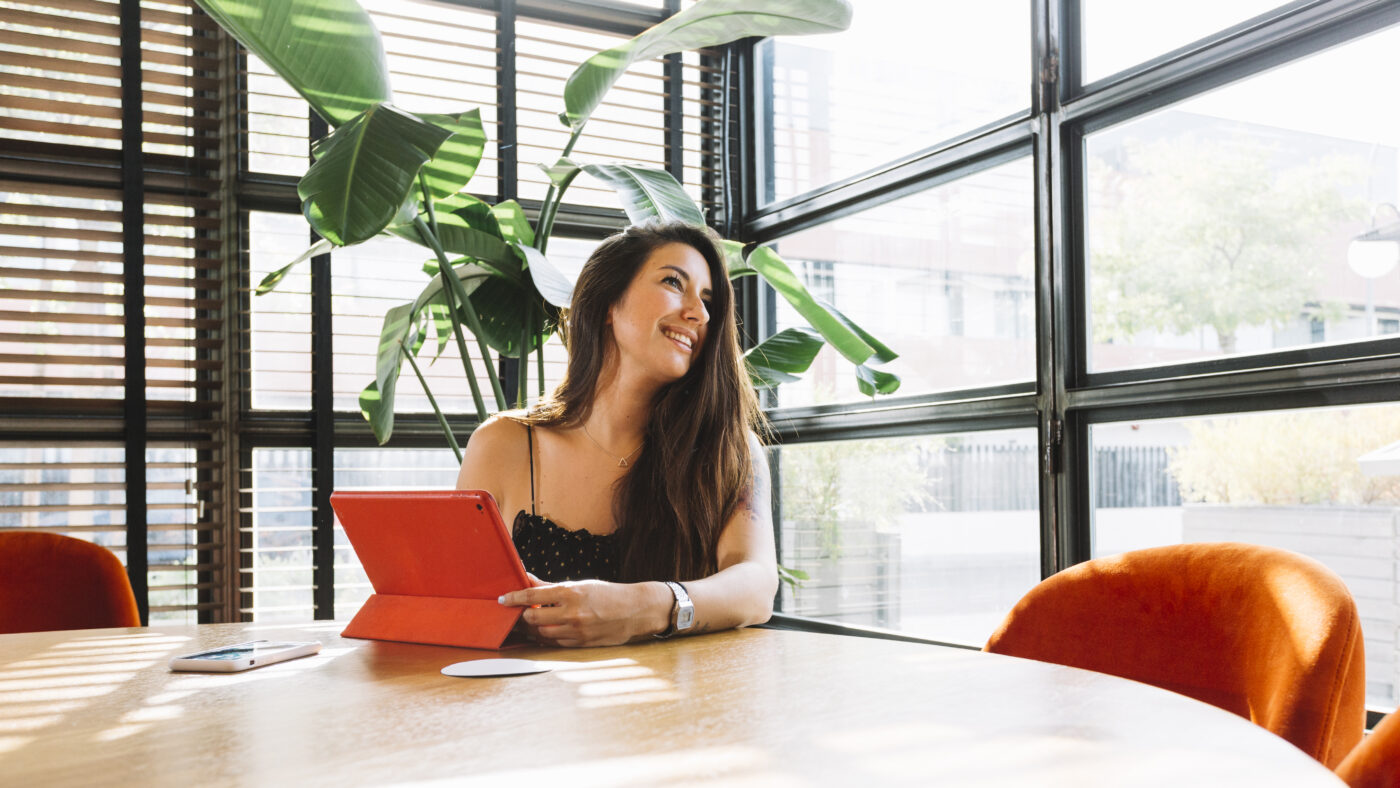 smiling young woman sitting restaurant with digital tablet