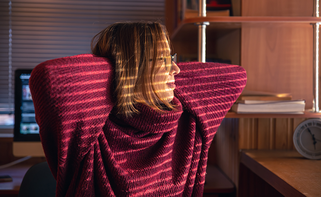 woman looks through blinds early morning sunlight